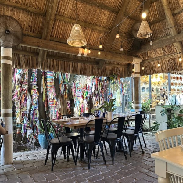 El Turco Turkish Food's dining area with a thatched roof, string lights, and colorful ribbons on pillars.