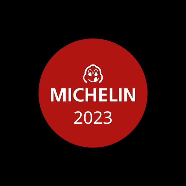 Red Michelin Guide 2023 logo with a smiling face on a black background.