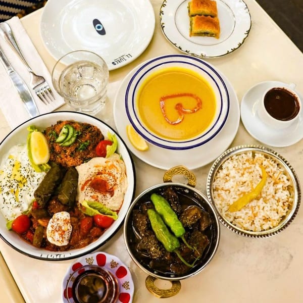 A table spread of Turkish dishes including soup, rice, meat stew, mezze platter, baklava, and Turkish coffee.