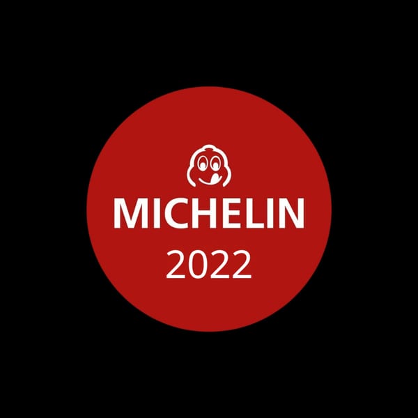 Red Michelin Guide 2022 emblem with the iconic Bibendum character on a black background.